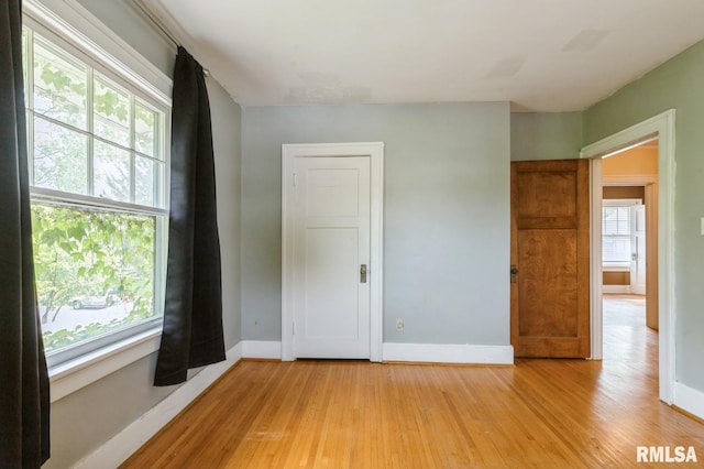 2505 Iowa St, Davenport, IA 52803 - unfurnished bedroom with multiple windows, light wood-style flooring, and baseboards