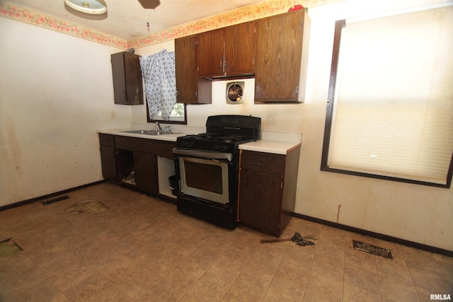 2630 N Concord St, Davenport, IA 52804 - kitchen with stainless steel range with gas stovetop, light countertops, a sink, and baseboards