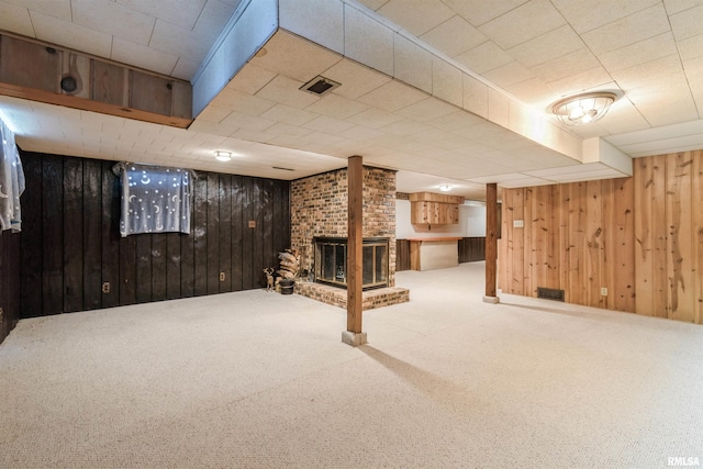 finished basement featuring wood walls, carpet flooring, and a fireplace