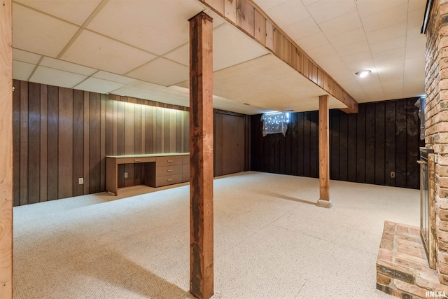 finished below grade area featuring wooden walls, a paneled ceiling, and carpet