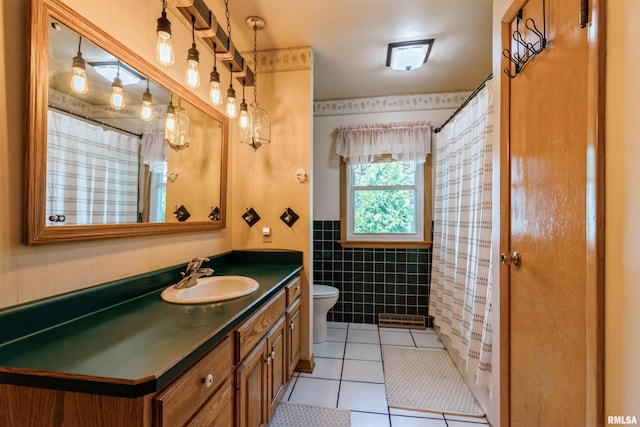 bathroom with tile patterned flooring, toilet, tile walls, vanity, and a wainscoted wall