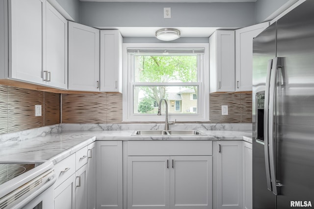2845 Washington Ln, Davenport, IA 52804 - kitchen featuring stainless steel refrigerator with ice dispenser, a sink, white cabinetry, backsplash, and light stone countertops