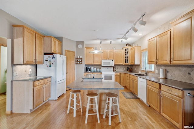 23835 284th Ave, Le Claire, IA 52748 - kitchen featuring white appliances, a sink, a kitchen breakfast bar, light wood-style flooring, and a center island