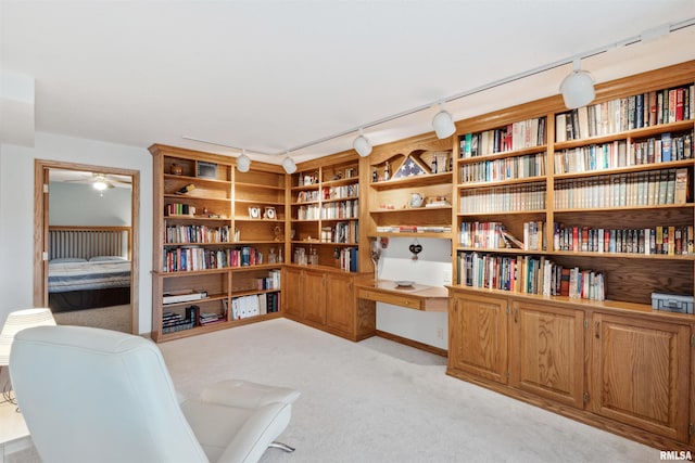 23835 284th Ave, Le Claire, IA 52748 - sitting room featuring rail lighting, light colored carpet, wall of books, and ceiling fan