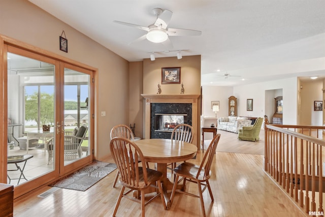 23835 284th Ave, Le Claire, IA 52748 - dining room featuring a ceiling fan, light wood-style flooring, rail lighting, a premium fireplace, and french doors