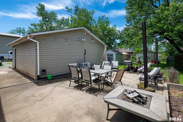 324 N Broadway, Goreville, IL 62939 - view of patio with a fire pit, a storage unit, outdoor dining space, an outbuilding, and fence
