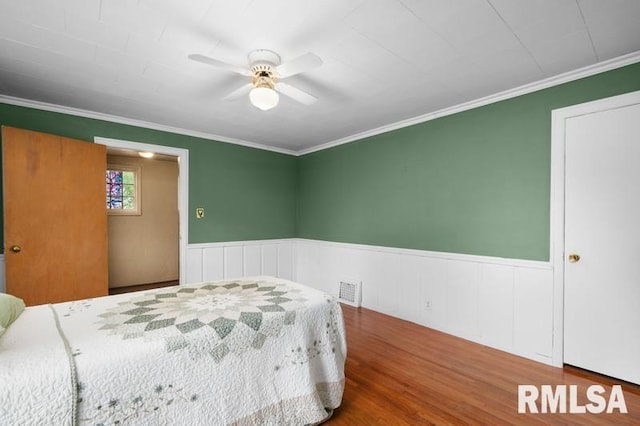 824 S State St, Geneseo, IL 61254 - bedroom featuring a wainscoted wall, wood finished floors, ornamental molding, and ceiling fan