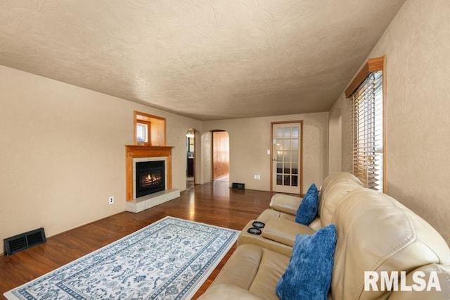 824 S State St, Geneseo, IL 61254 - living area with arched walkways, wood finished floors, a warm lit fireplace, and a textured ceiling