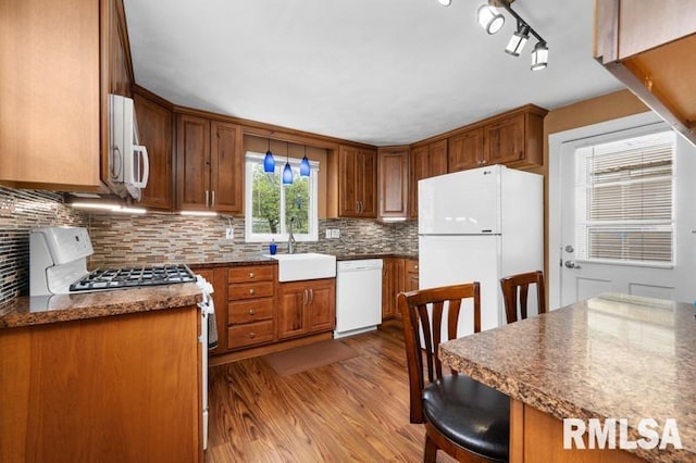 824 S State St, Geneseo, IL 61254 - kitchen featuring white appliances, a sink, wood finished floors, tasteful backsplash, and brown cabinets