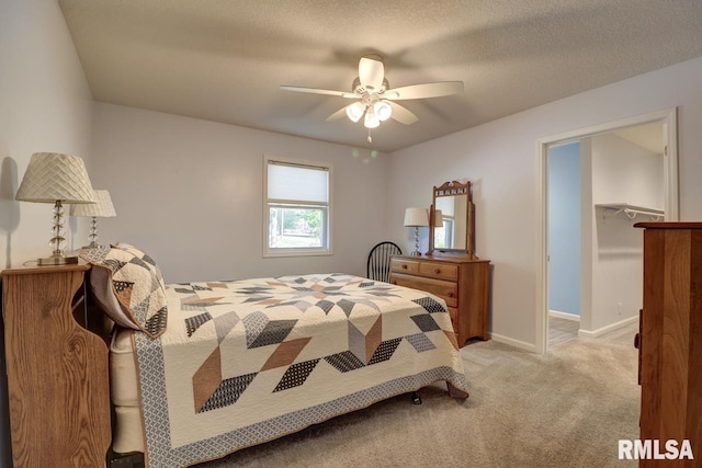 carpeted bedroom with a spacious closet, baseboards, and a ceiling fan