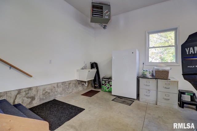 garage with freestanding refrigerator, a sink, and a heating unit