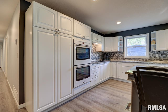 kitchen featuring double oven, open shelves, light wood-type flooring, backsplash, and white cabinets