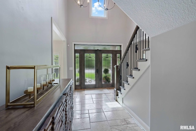 6531 Eagle Ridge Rd, Bettendorf, IA 52722 - entryway featuring a high ceiling, french doors, a chandelier, stone tile flooring, and stairs