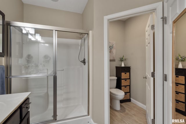 11 Musket Ct, Le Claire, IA 52753 - bathroom featuring a stall shower, toilet, wood finished floors, and baseboards