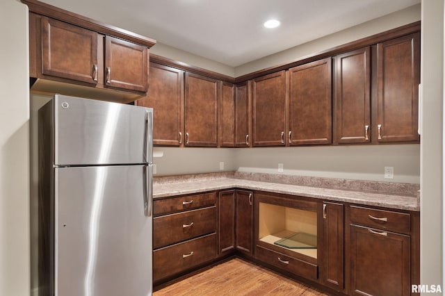 11 Musket Ct, Le Claire, IA 52753 - kitchen with freestanding refrigerator, light wood-style floors, dark brown cabinetry, and recessed lighting