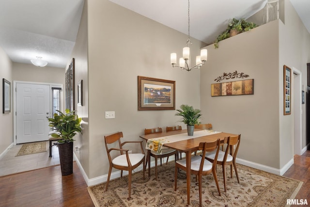 11 Musket Ct, Le Claire, IA 52753 - dining room featuring wood finished floors, baseboards, a chandelier, and high vaulted ceiling