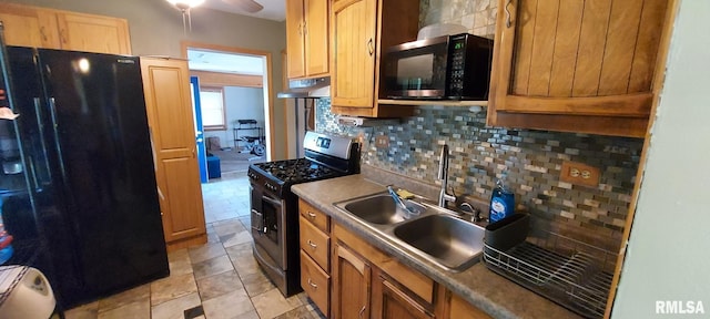 601 E St S, Kewanee, IL 61443 - kitchen featuring black fridge, stainless steel range with gas cooktop, under cabinet range hood, a sink, and tasteful backsplash