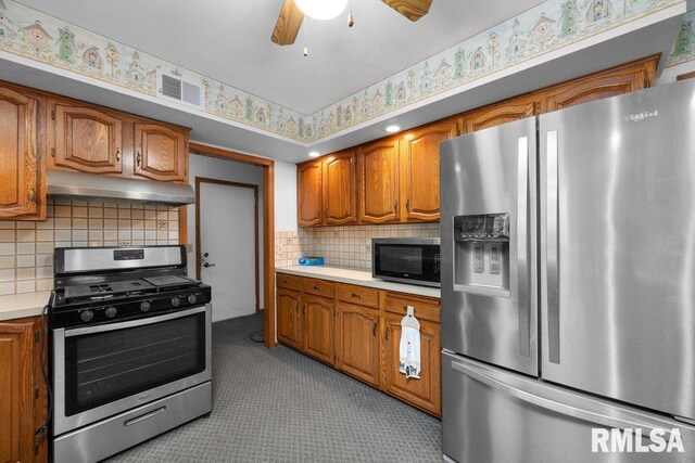 5117 Woodland Ave, Davenport, IA 52807 - kitchen featuring stainless steel appliances, under cabinet range hood, light countertops, and brown cabinetry