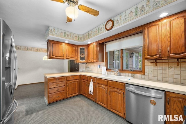 5117 Woodland Ave, Davenport, IA 52807 - kitchen with stainless steel appliances, a sink, brown cabinetry, carpet floors, and light countertops