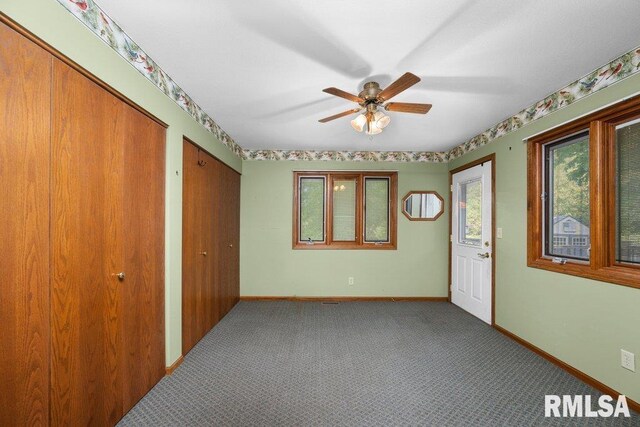 5117 Woodland Ave, Davenport, IA 52807 - unfurnished bedroom featuring two closets, baseboards, carpet floors, and ceiling fan