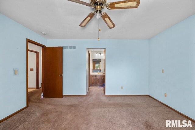 5117 Woodland Ave, Davenport, IA 52807 - unfurnished bedroom featuring carpet floors, baseboards, ensuite bathroom, and a ceiling fan