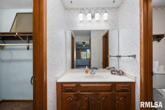 5117 Woodland Ave, Davenport, IA 52807 - bathroom with wallpapered walls, vanity, toilet, and a ceiling fan