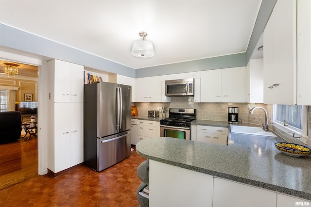 2615 12th St, Moline, IL 61265 - kitchen featuring stainless steel appliances, a sink, a peninsula, dark flooring, and white cabinetry