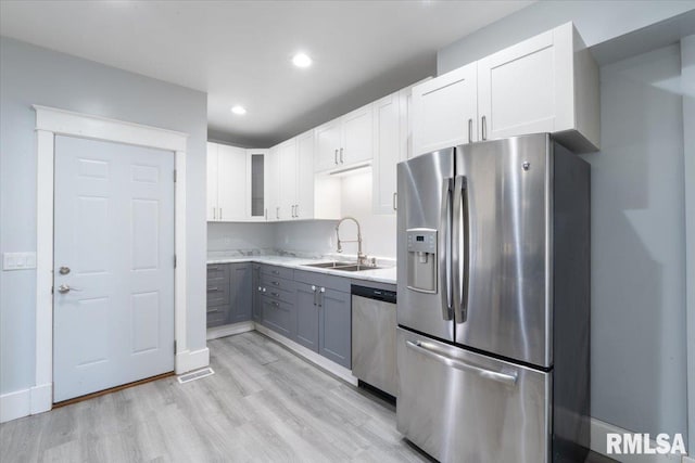 1720 Davie St, Davenport, IA 52804 - kitchen featuring appliances with stainless steel finishes, a sink, light wood-type flooring, white cabinets, and glass insert cabinets