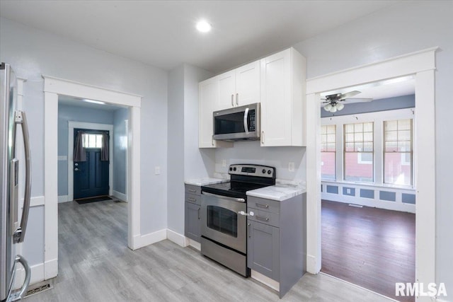 1720 Davie St, Davenport, IA 52804 - kitchen with appliances with stainless steel finishes, gray cabinetry, light wood-type flooring, a ceiling fan, and baseboards