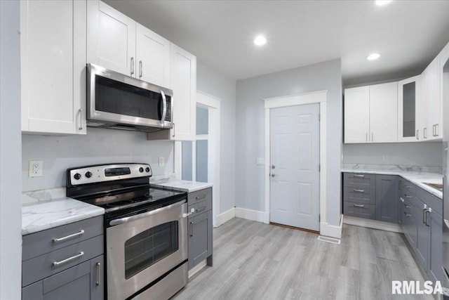 1720 Davie St, Davenport, IA 52804 - kitchen with stainless steel appliances, gray cabinetry, light stone counters, light wood finished floors, and white cabinetry