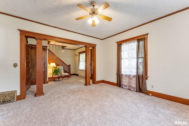 314 W Locust St, Cambridge, IL 61238 - carpeted spare room with stairs, decorative columns, crown molding, a ceiling fan, and a textured ceiling