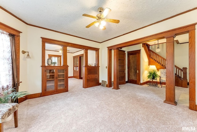 314 W Locust St, Cambridge, IL 61238 - unfurnished living room featuring decorative columns, carpet flooring, stairs, a ceiling fan, and a textured ceiling