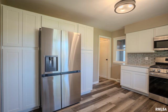 8501 49th St, Coal Valley, IL 61240 - kitchen featuring stainless steel appliances, backsplash, light wood-style floors, and white cabinetry