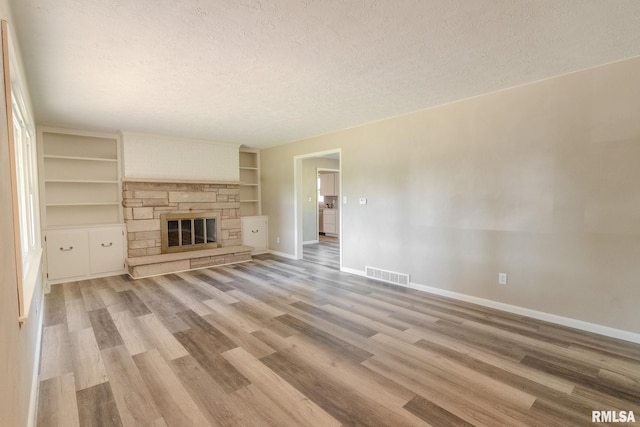 8501 49th St, Coal Valley, IL 61240 - unfurnished living room with a textured ceiling, baseboards, light wood finished floors, and built in shelves