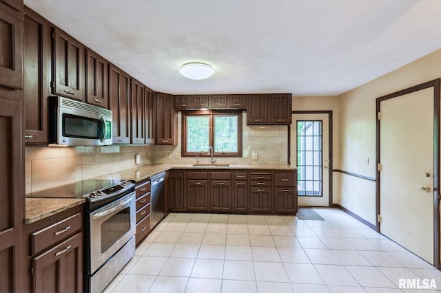 28009 230th St, Le Claire, IA 52753 - kitchen with stainless steel appliances, a sink, decorative backsplash, light stone counters, and dark brown cabinets