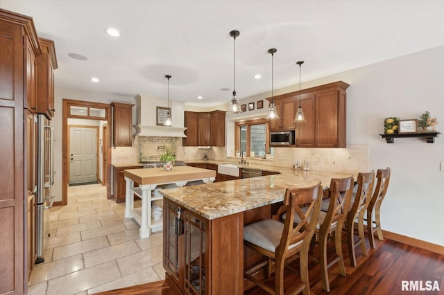 27998 229th St, Le Claire, IA 52753 - kitchen with appliances with stainless steel finishes, a peninsula, tasteful backsplash, baseboards, and recessed lighting