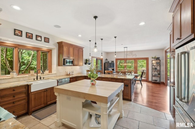 27998 229th St, Le Claire, IA 52753 - kitchen with appliances with stainless steel finishes, a peninsula, wooden counters, a sink, and brown cabinets