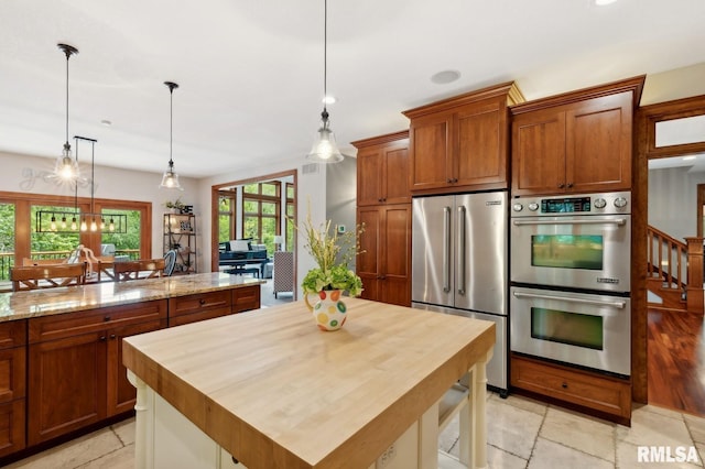 27998 229th St, Le Claire, IA 52753 - kitchen featuring appliances with stainless steel finishes, brown cabinets, butcher block counters, and pendant lighting