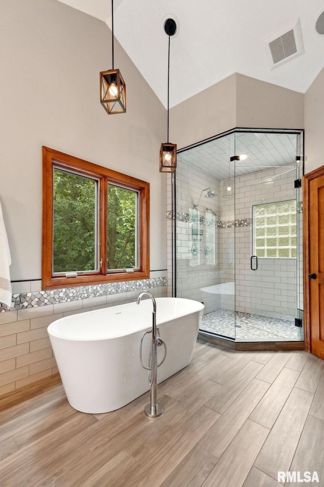 27998 229th St, Le Claire, IA 52753 - bathroom with tile walls, a stall shower, a freestanding bath, wood finished floors, and wainscoting