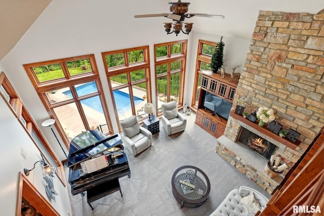 27998 229th St, Le Claire, IA 52753 - living room with a stone fireplace, a ceiling fan, a towering ceiling, and carpet floors