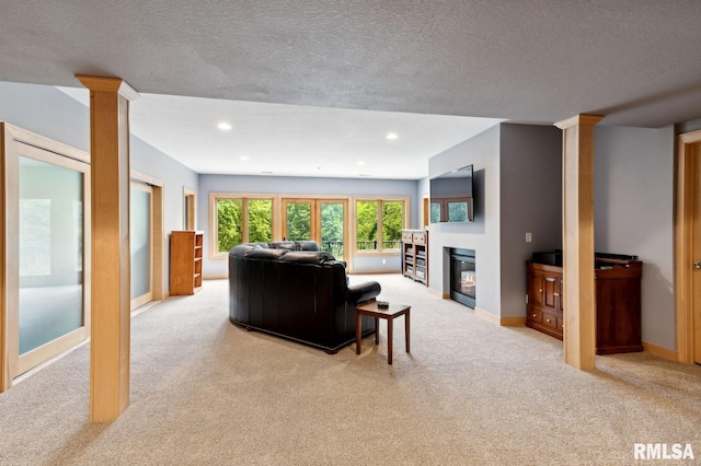27998 229th St, Le Claire, IA 52753 - living area with light colored carpet, ornate columns, baseboards, a textured ceiling, and a glass covered fireplace
