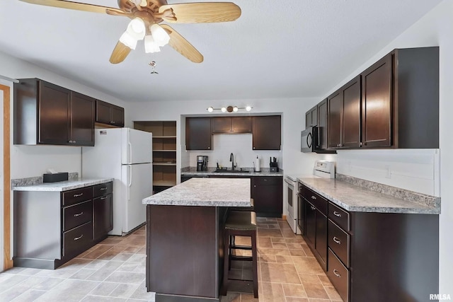 21704 283rd Ave, Le Claire, IA 52753 - kitchen with white appliances, a sink, dark brown cabinetry, a center island, and a kitchen breakfast bar