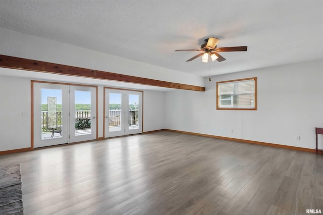 21704 283rd Ave, Le Claire, IA 52753 - empty room with plenty of natural light, a ceiling fan, baseboards, light wood-style flooring, and beamed ceiling