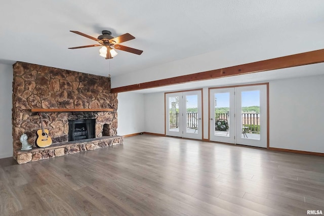 21704 283rd Ave, Le Claire, IA 52753 - unfurnished living room with a ceiling fan, a stone fireplace, baseboards, and wood finished floors