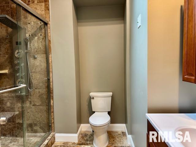 1203 13th Ave S, Clinton, IA 52732 - full bathroom with vanity, toilet, a shower stall, and baseboards