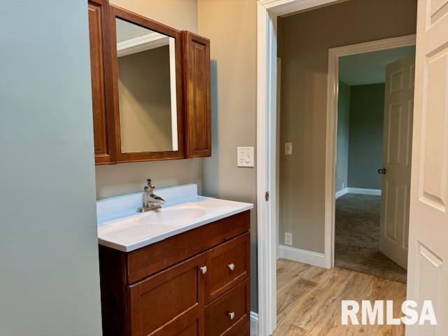 1203 13th Ave S, Clinton, IA 52732 - bathroom featuring vanity, wood finished floors, and baseboards
