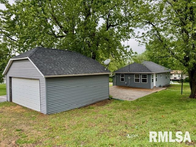 1203 13th Ave S, Clinton, IA 52732 - rear view of property with an outbuilding, a detached garage, a lawn, a patio, and roof with shingles