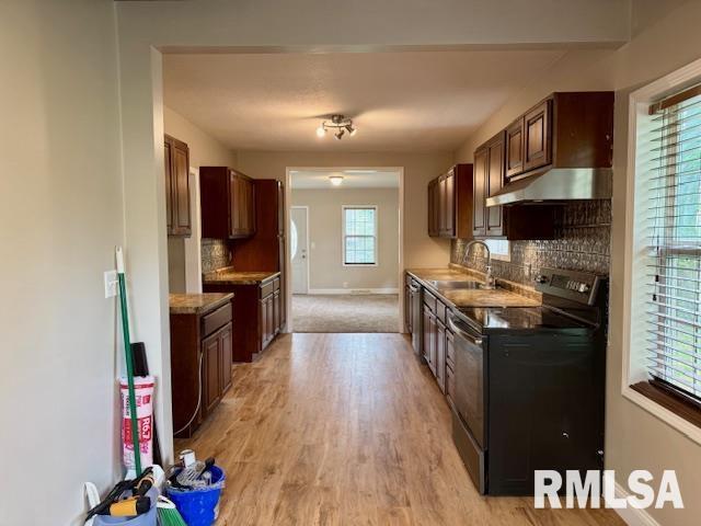 1203 13th Ave S, Clinton, IA 52732 - kitchen featuring black electric range, a sink, under cabinet range hood, light wood-style floors, and tasteful backsplash