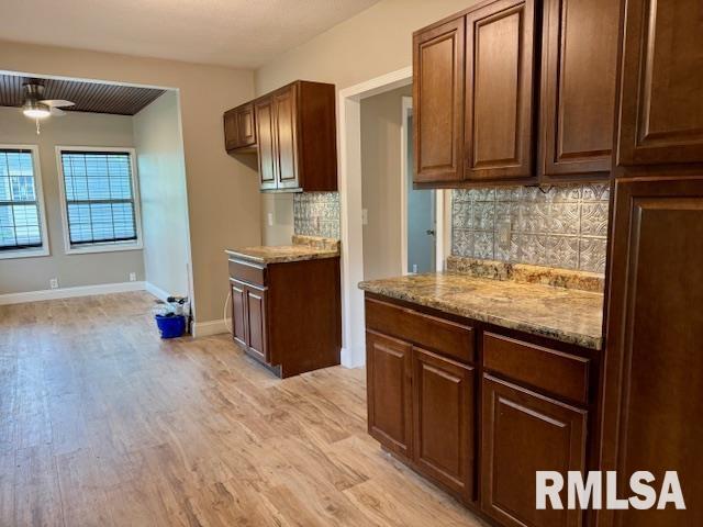 1203 13th Ave S, Clinton, IA 52732 - kitchen with light wood-style flooring, tasteful backsplash, light stone countertops, and baseboards