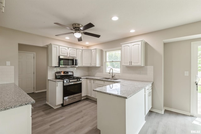 301 5th St, Matherville, IL 61263 - kitchen featuring stainless steel appliances, a sink, a peninsula, white cabinetry, and light wood-style flooring